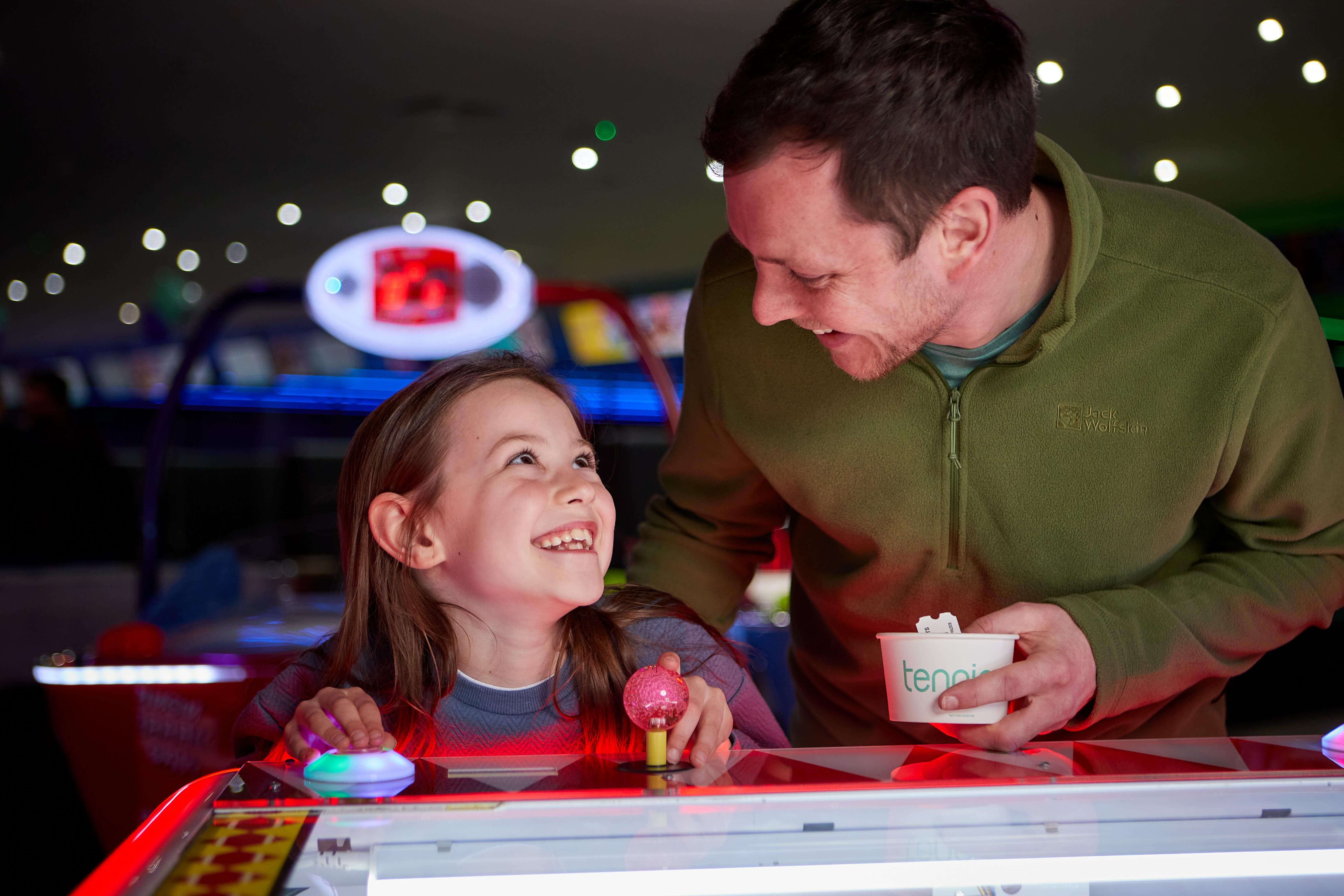 Father And Daughter Play Air Hockey In The Arcade