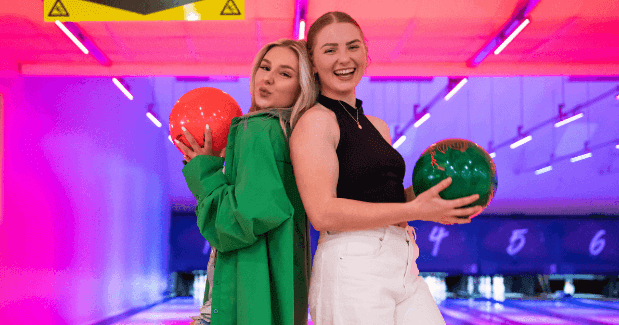 2 Girls Posing With Bowling Balls In Front Of Lane At Tenpin (1)