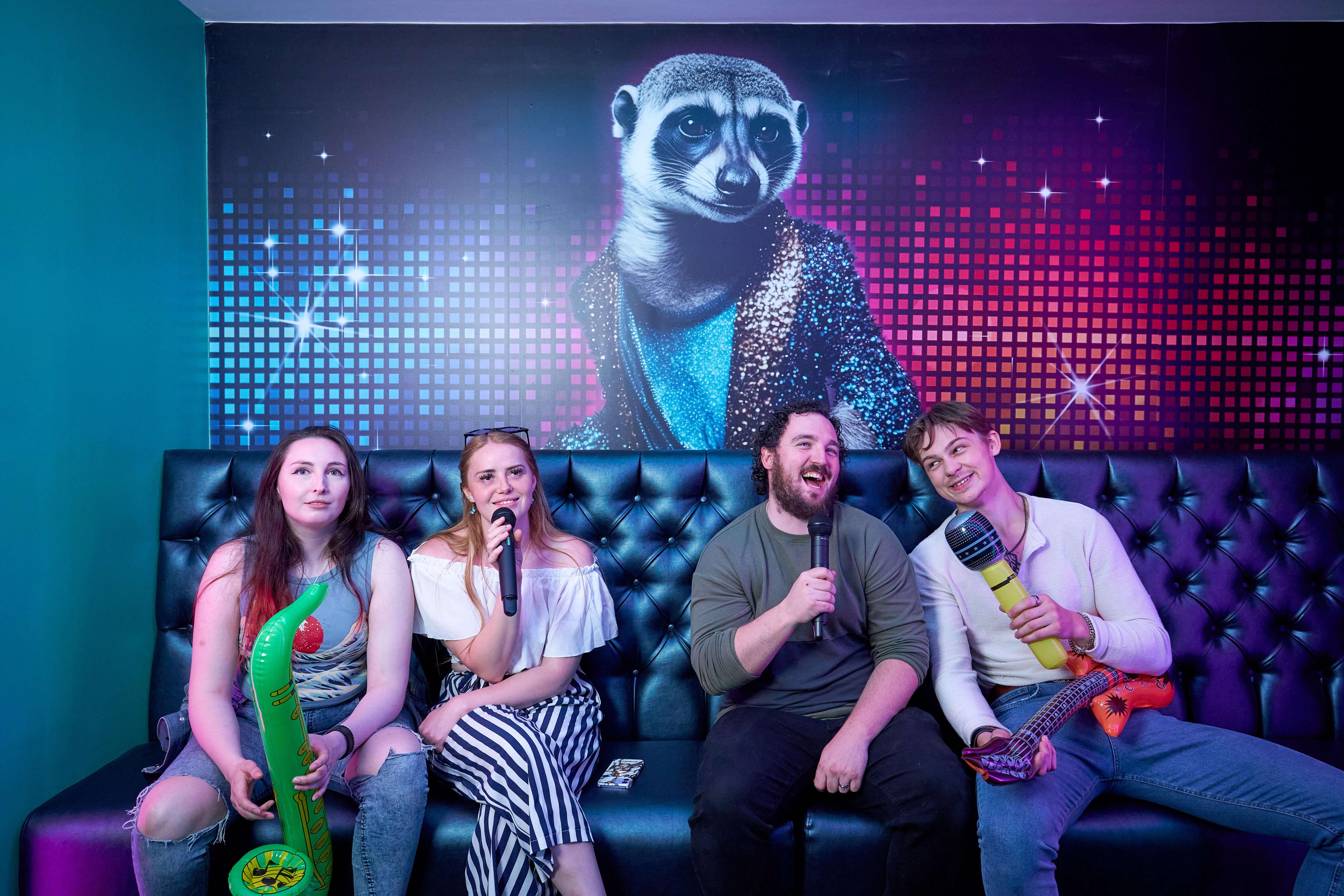 Group of friends singing in karaoke room with props