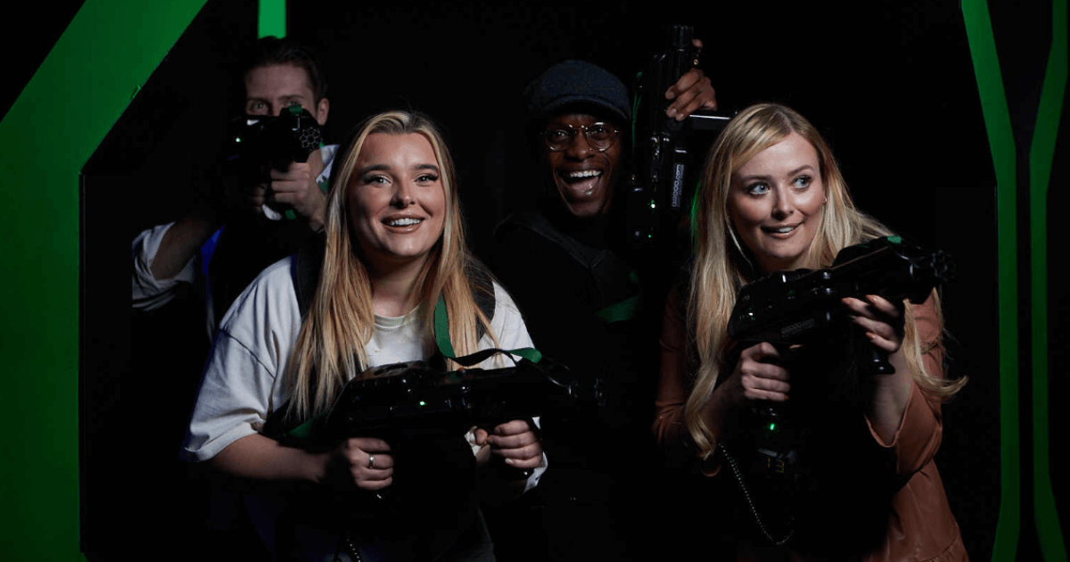 A Group Of People Posing For A Photo In Front Of A Green Screen Holding Laser Tag Guns At Tenpin (1)