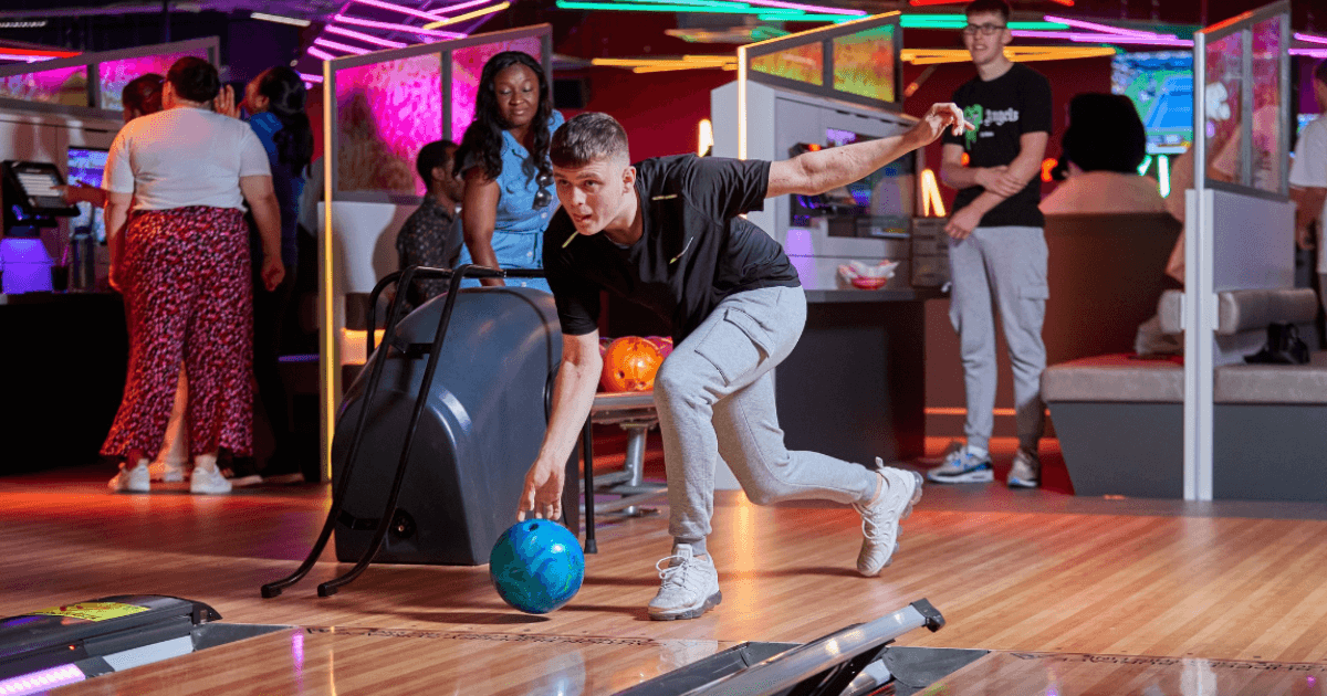 Young Man Rolling Blue Ball Down A Bowling Lane At Tenpin (2)