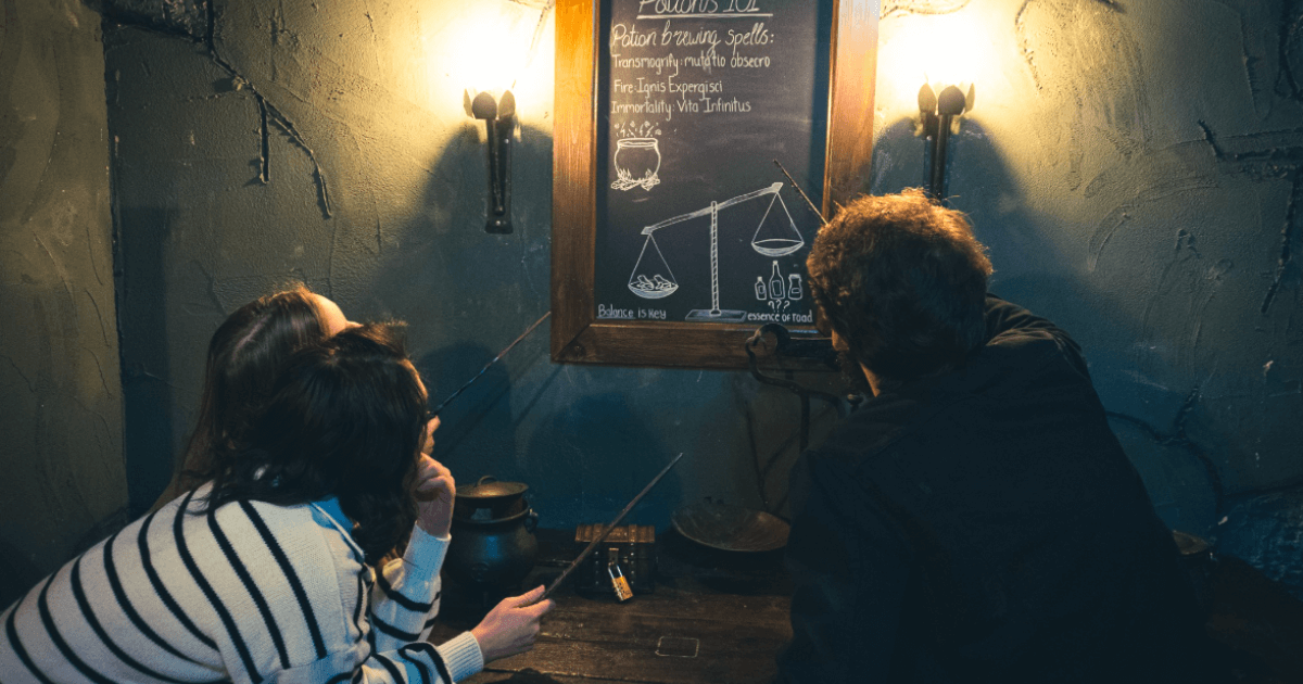 Three Friends Working On A Puzzle Drawn On A Black Board Within An Escape Room (1)