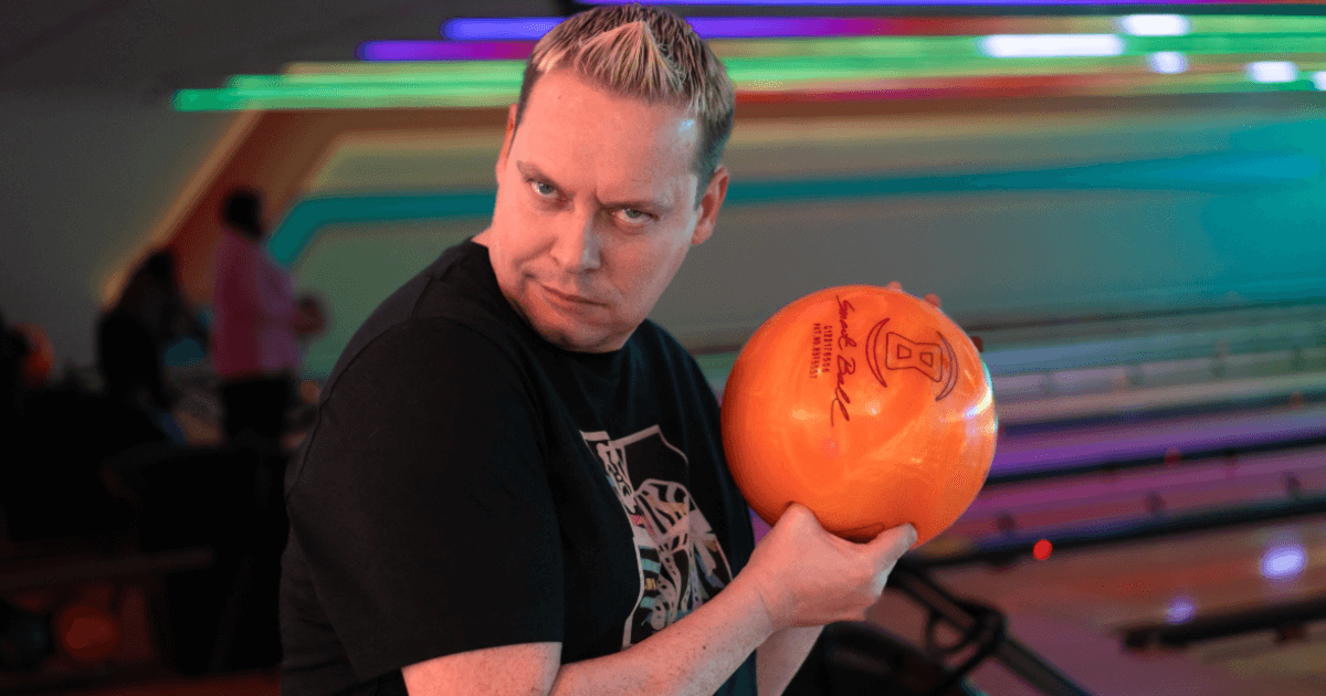 Man Pulling Funny Face While Holding An Orange Bowling Ball (1)