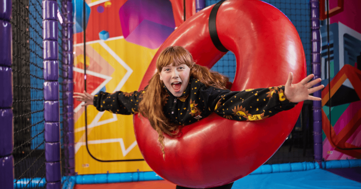 Young Girl Swinging Inside A Red Ring In A Soft Play (1)