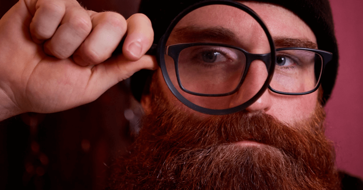 Man With Beard Looking Through A Magnifying Glass (1)